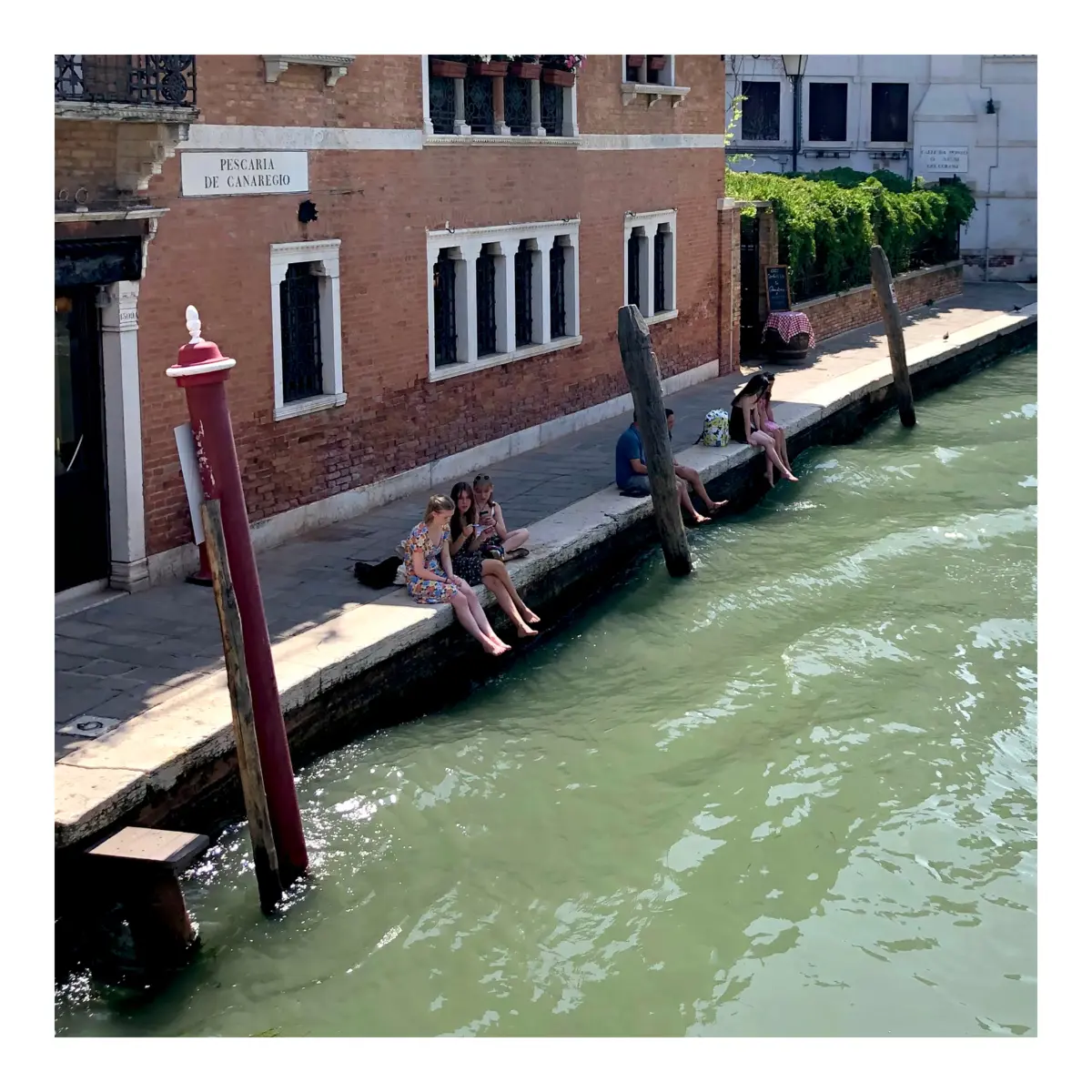 Girls sitting at the canal in Venice