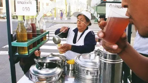 Night market scene in Peru with people buying warm emoliente from a smiling vendor and paying with crypto