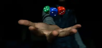 Man's hand with three dice hovering above it. Photo by El Pepe on Unsplash