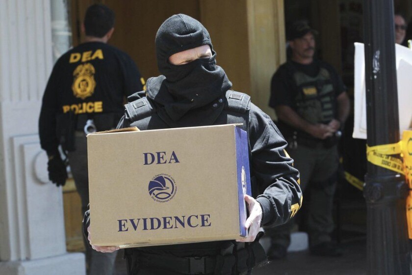 DEA agent carrying box of evidence after the raid