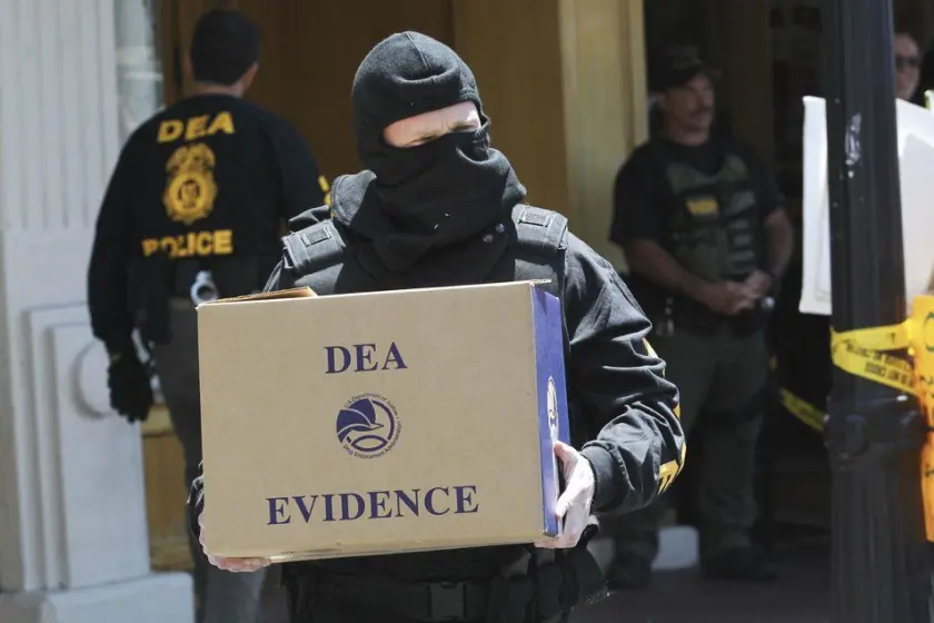 DEA agent carrying box of evidence after the raid