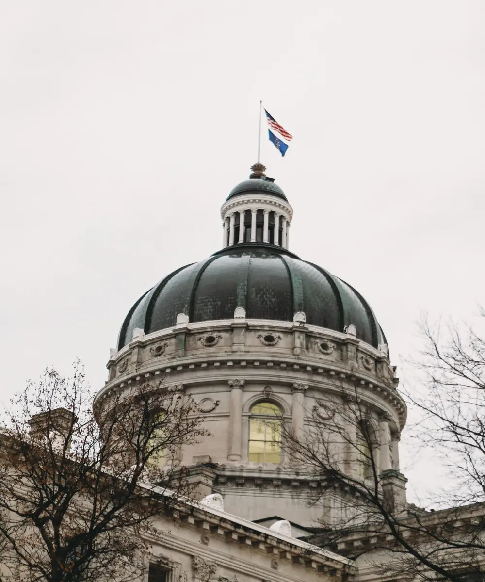 dome of indiana statehouse with american flag and indiana state flag on top