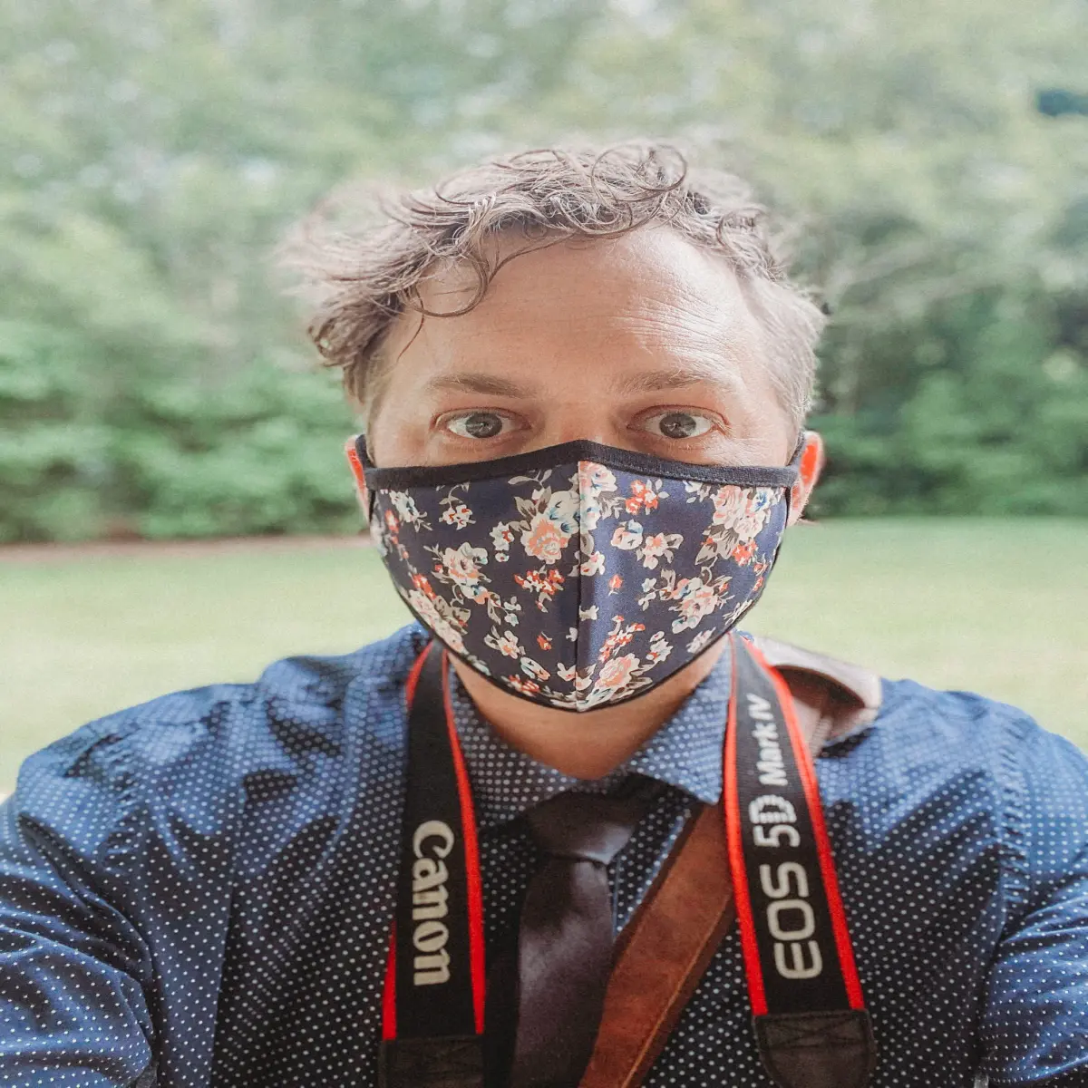 man with camera in floral print mask