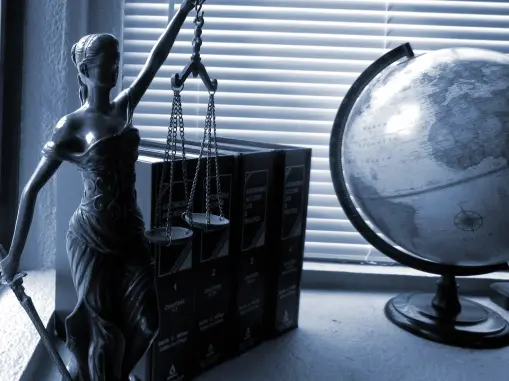 a statue of lady justice along with some books and a globe