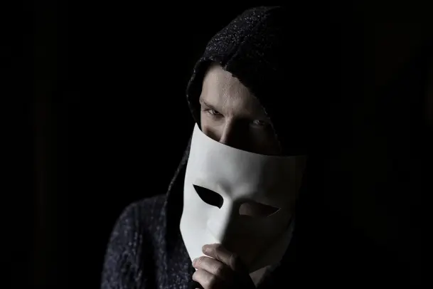 a man hiding half of his face with a white mask