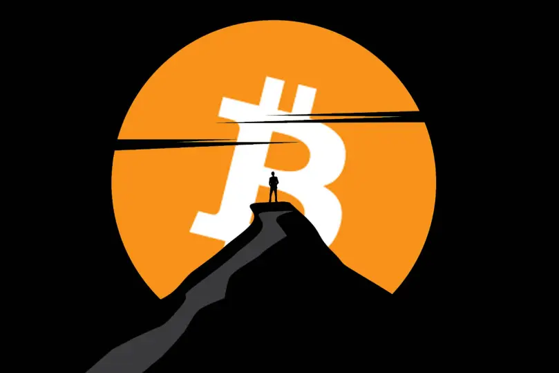 Silhouette of a man standing on top of a mountain looking at a Bitcoin moon.