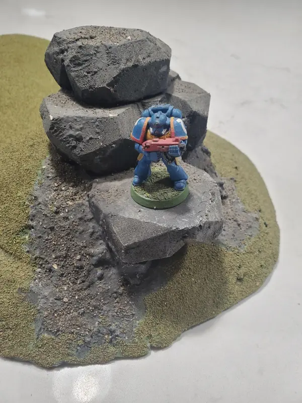 An example of using the protruding rock to position a miniature (WH40K scenery)